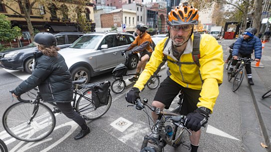 Cyclists ride along a protected bike lane in the city.
