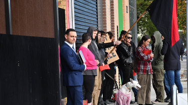 A real estate agent holds an open for inspection at Melbourne Anarchist Club as members protest the sale of the building.