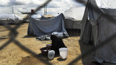 A woman washes clothes at the fence line of the foreign section of al-Hawl camp in Syria.