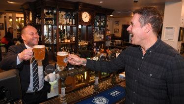 Federal treasurer Josh Frydenberg (left) cheers former AFL footballer Matthew Richardson at the Glenferrie Pub in Melbourne on Monday.