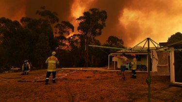 NSW Fire and Rescue firefighters monitor the situation from Luke Dinham's home as the Green Wattle Creek fire approaches Yanderra.