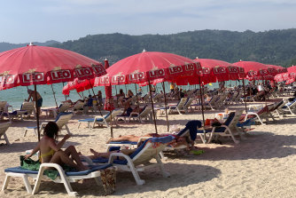 Tourists lounge under umbrellas along Patong Beach in Phuket.