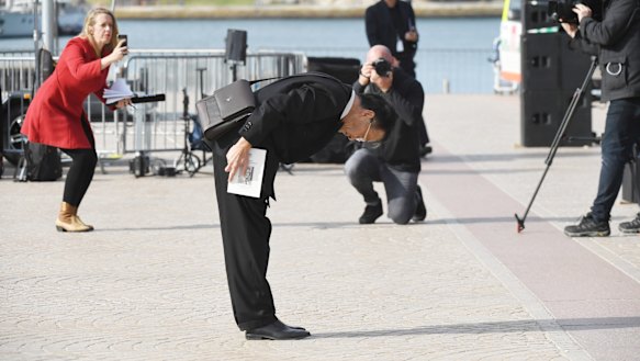 A man bows towards the screen at the end of Bob Hawke's memorial service.