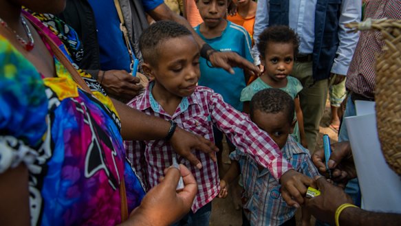 A boy's finger is marked with black after a Polio vaccination.