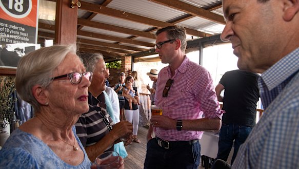 NSW Treasurer Dominic Perrottet, background, meets locals at the Nevertire Pub on a road trip from Dubbo to Bourke.