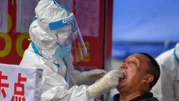 A medical worker collects a sample for COVID-19 testing at the Tongji community in Shulan in China's Jilin Province. 