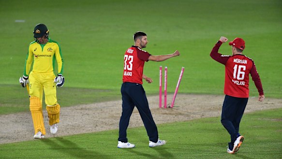 England's Mark Wood, center, celebrates with captain Eoin Morgan, right, the dismissal of Australia's Alex Carey. 