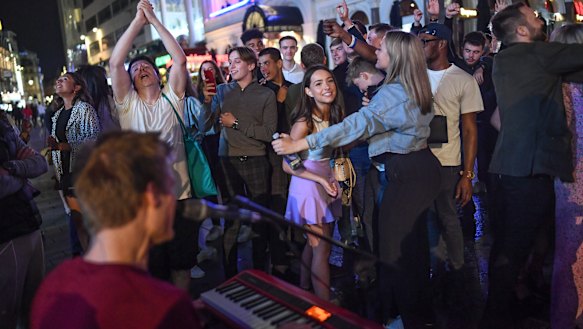 People watch a busker in London's Leicester Square. Most gatherings of more than six people have now been banned.