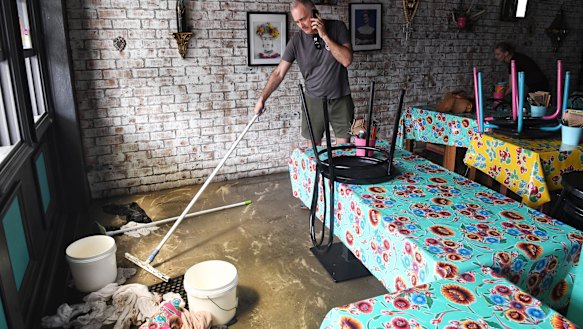 Ben Coles cleans up his restaurant in Narrabeen after Sunday’s flooding.