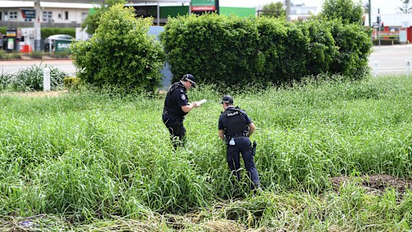 Police examine the scene where two bodies were found in a drain behind the Aitkenvale Library in Townsville.