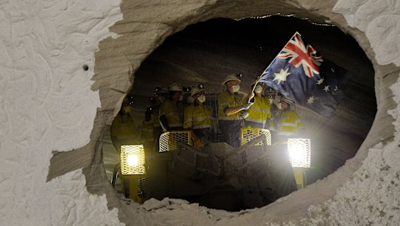A worker on one of the two roadheaders waves the Australian flag moments after smashing through sandstone connecting two sections of the M4-M5 Link.