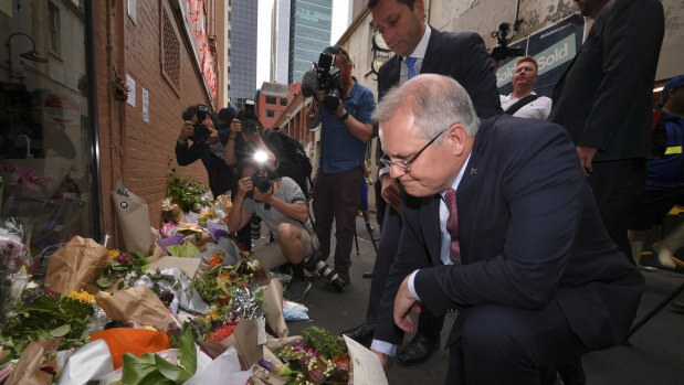 Scott Morrison places flowers outside Pellegrini's on Tuesday morning.