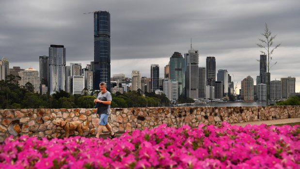A  man is seen walking his dog at the Kangaroo Point cliffs as storm clouds gather over the Brisbane CBD.