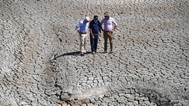 Water Resources Minister David Littleproud examines a dried-up river bed, with Treasurer Josh Frydenberg and farmer Dino Rizzato, near Stanhope in Queensland, on Friday.