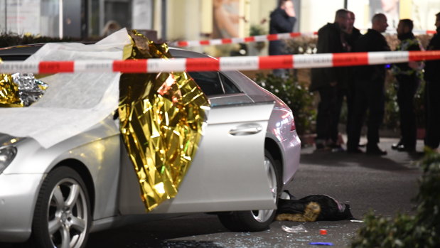 A car that was damaged in the shooting is covered in thermo foil and surrounded by debris at the scene in Hanau, Germany.