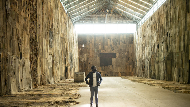 Portrait of Ibrahim Mahama with his artwork No Friend but the Mountains at Cockatoo Island.  