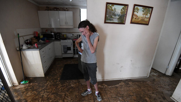Sue Pollard becomes emotional as she walks around her flood-affected house in the suburb of Hermit Park in Townsville