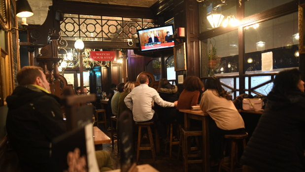 People watch Boris Johnson's announcement from the Red Lion Pub in London.