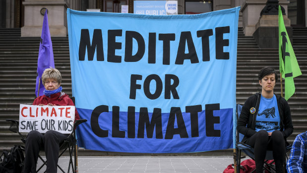 Protesters meditate for climate change action on the steps of Parliament on Monday.