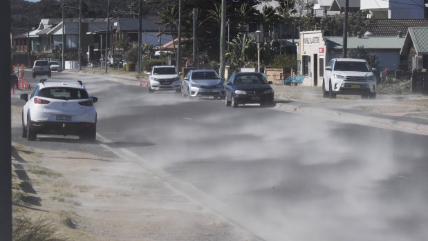 Sand is blown down Prince Charles Parade in Kurnell as winds made conditions uncomfortably cool for many on Friday.
