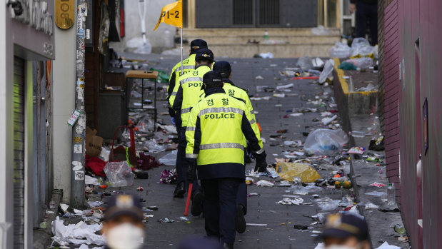 Police officers work on Sunday at the scene of a fatal crowd surge in Seoul. 