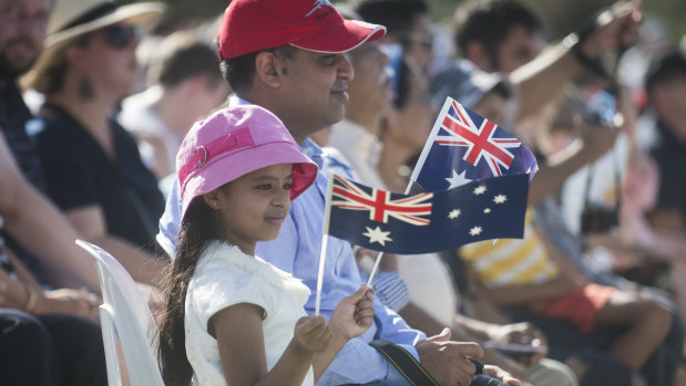 Ria Francis waves the Australian flag at the national citizenship ceremony in Commonwealth Park on Saturday morning.