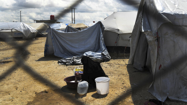 A woman washes clothes in front of her tent at the fence line of the foreign section of al-Hawl camp in Syria.