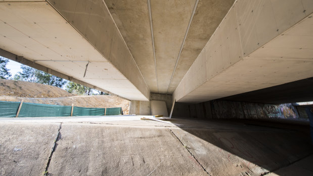 Two sets of cable trunking – enclosures used to protect electrical cables – fixed to the underside of a bridge on Flemington Road. The area between the two shows the bridge's regular height.