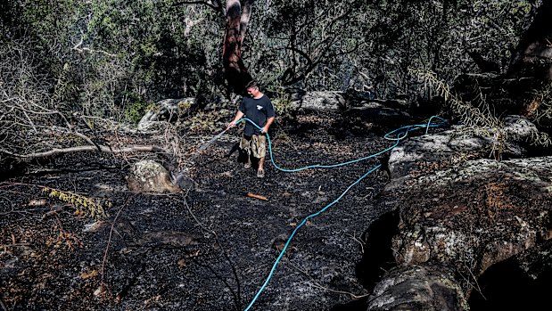 Justin Frith hoses down an area behind his home in Menai in Sydney.