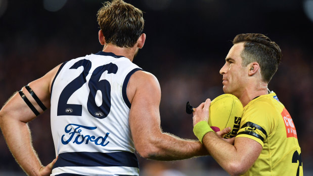 The umpire takes the ball from Tom Hawkins after a controversial off-the-ball free kick.