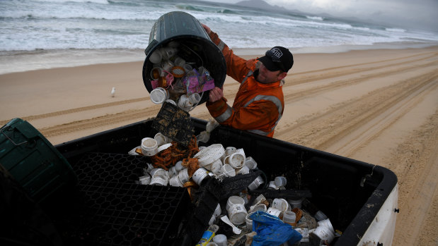 Clean up contractor Derrick Kennedy clearing debris from the beach at Hawks Nest near Port Stephens.