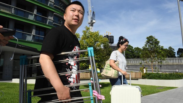 Qi, left, leaves Opal Tower on Friday, as he weighs up whether to return permanently.