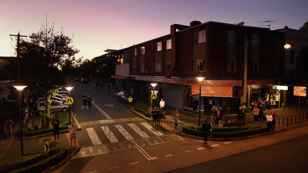 People listen to bugler Sarah Brown as she plays The Last Post from the balcony of The Royal Hotel on Norton Street in Leichhardt at dawn on ANZAC Day. Leichhardt.