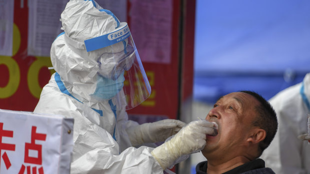 A medical worker collects a sample for COVID-19 testing at the Tongji community in Shulan in China's Jilin Province. 