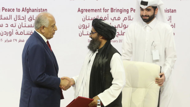 US peace envoy Zalmay Khalilzad, left, and Mullah Abdul Ghani Baradar, the Taliban group's top political leader, shake hands after signing a peace agreement in Doha, Qatar, in February.