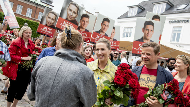 Mette Frederiksen, centre, gives away roses to voters in the last minutes of her campaign in her hometown of Aalborg, along with its mayor, Thomas Kastrup-Larsen, right.