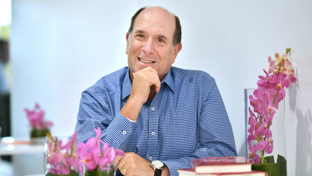 Kronos chief executive and chairman Aron Ain at the Grand Prix with a stack of his books 'Work Inspired'