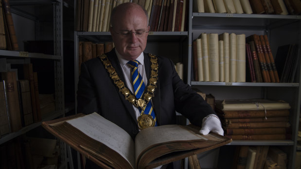 Parramatta Lord Mayor Andrew Wilson holding a book with the first council minutes. 