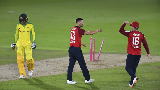 England's Mark Wood, center, celebrates with captain Eoin Morgan, right, the dismissal of Australia's Alex Carey. 