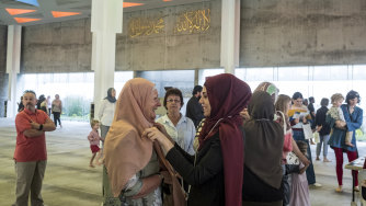 Zainab Badra helps Barbara Hughes of Williamstown put on a hijab at the Newport mosque.