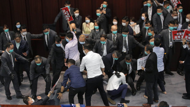 Pro-establishment politician, Starry Lee, centre in yellow, speaks as scuffles break out in Hong Kong.