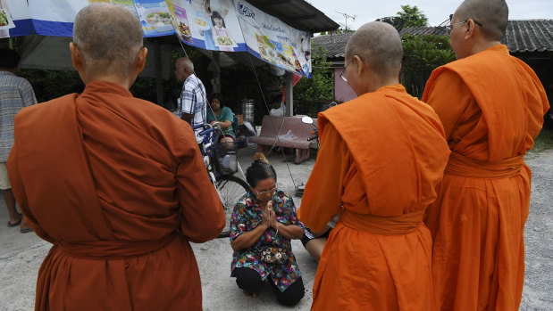 A woman kneels as she receives a blessing from female Theravada Buddhist monks.