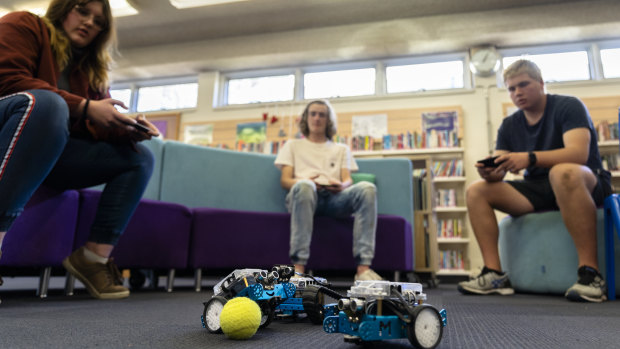Alfred Deakin High School Year 10 students Shanti Geoghegan (left), Tom Hilton, and Liam Ayres play a game of soccer with their phone operated robots.