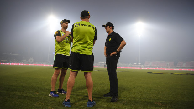 Officials are seen on the field of play as smoke haze forced the stoppage of the Big Bash League cricket match at Manuka Oval in Canberra on Saturday.