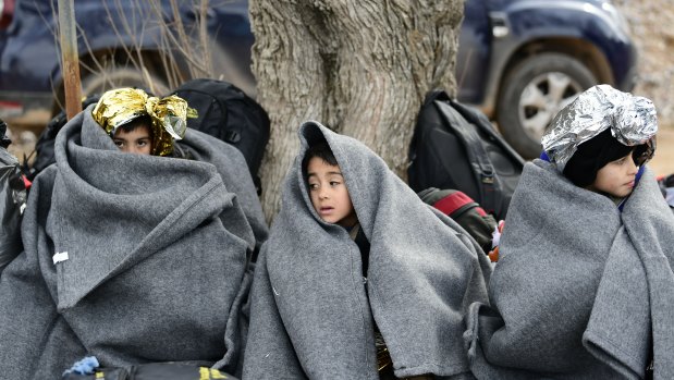 Children from Afghanistan use blankets to warm themselves after an arrival of a dinghy at the village of Skala Sikaminias, on the Greek island of Lesbos, after crossing the Aegean sea from Turkey.