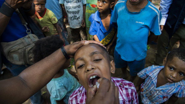 A child in Papua New Guinea receives a polio vaccine. The coronavirus outbreak threatens to reverse decades of global progress in alleviating poverty.