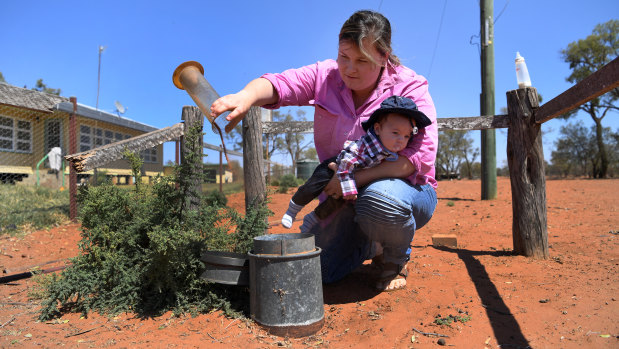 Kate Stokes with her son Tom as she empties sand and dust out of their rain gauge on their drought-affected property near Bollon in south-west Queensland.