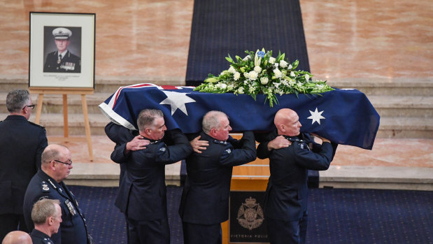 Former chief commissioner Mick Miller's coffin is carried out after his funeral. 