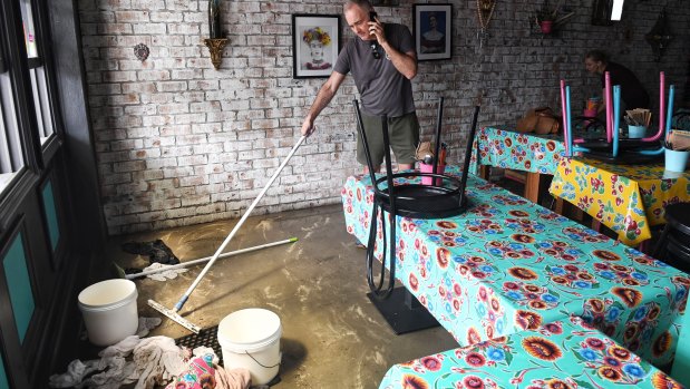 Ben Coles cleans up his restaurant in Narrabeen after Sunday’s flooding.