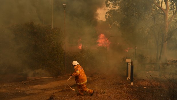 A RFS firefighter in front of a house that could not be saved from fire on Thursday on the outskirts of Bargo.